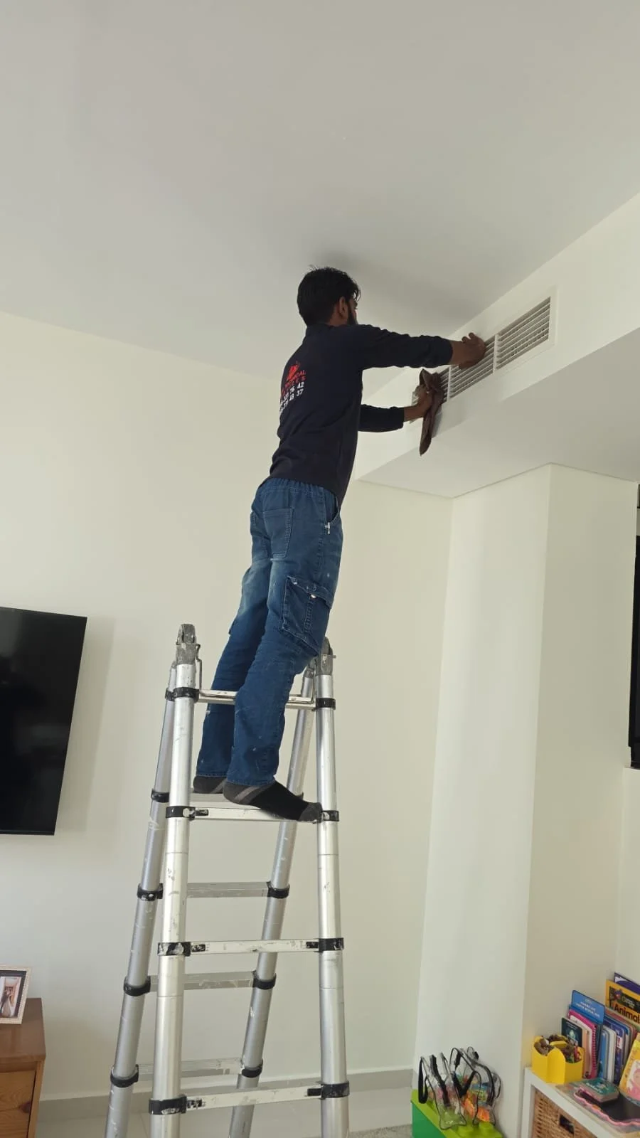AC technician servicing an air conditioning vent inside a Dubai villa